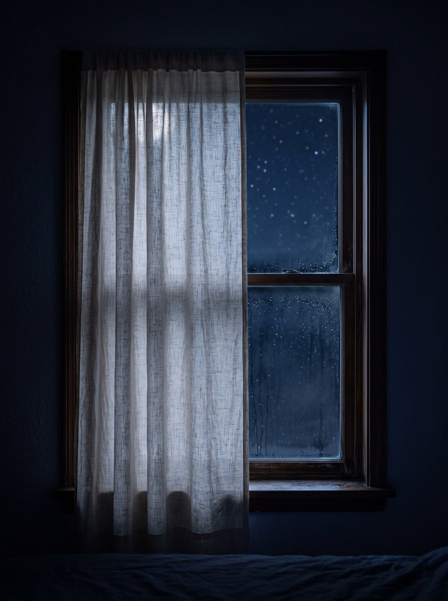 A linen curtain drawn across a bedroom window at night, stars beyond the glass